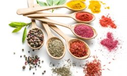 Assortment of colorful spices in the wooden spoons on the white background.